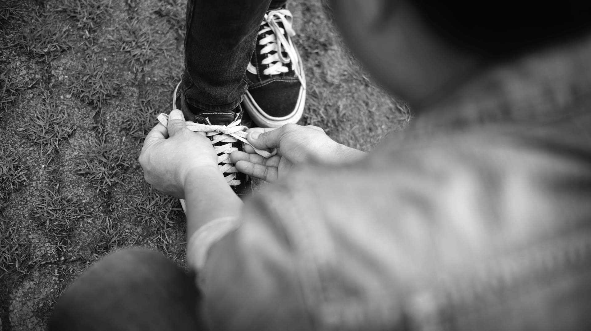 Primer plano de las manos de un hombre atando los cordones de la zapatilla de un niño